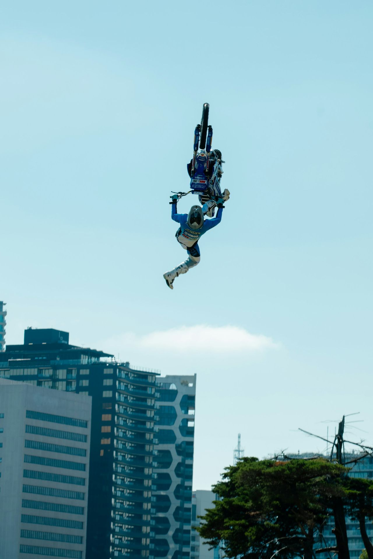 A motocross rider performs a backflip in mid-air.